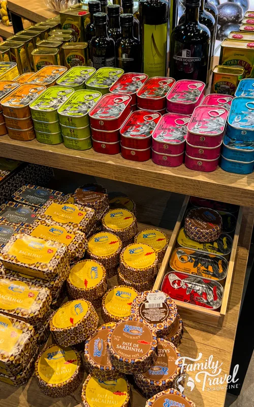 Table in shop with colorful canned fish and bottles and tins of olive oil 