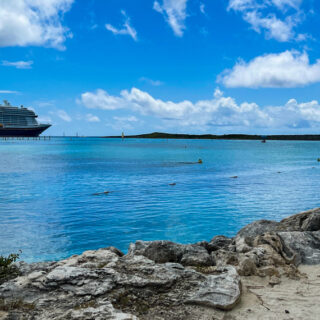 The Disney Wish docked at Castaway Cay with the beach in the foreground and a blue sky