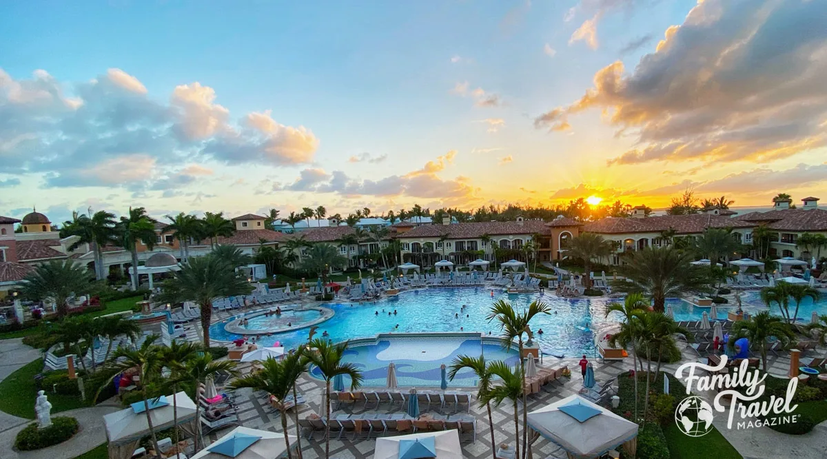 Beaches Turks and Caicos Italian village pool at sunset, surrounded by beach chairs and cabanas