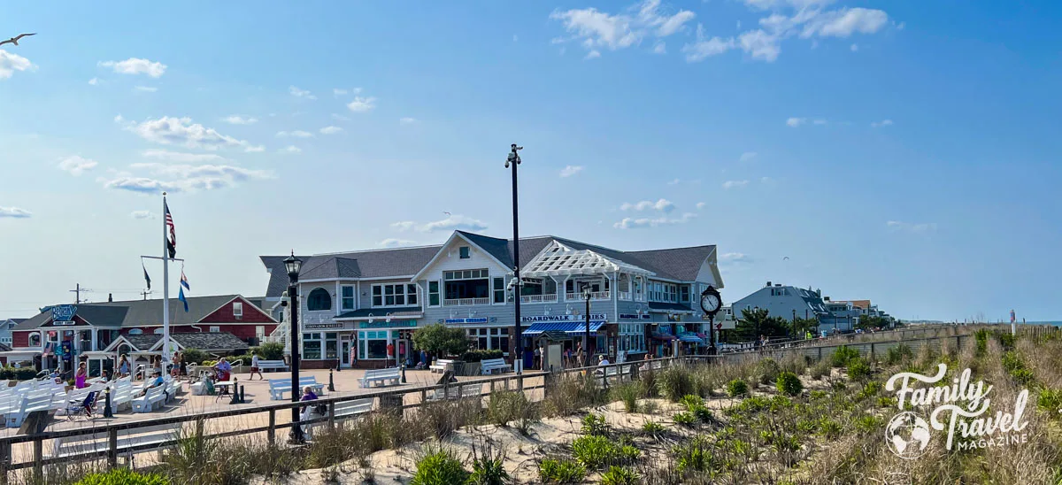 Boardwalk shops and food stands from the beach with sand and seagrass in foreground