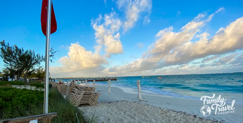 Beach with chairs stacked and a pier. 