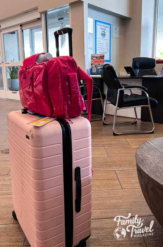 pink backpack sideways on a pink roller bag