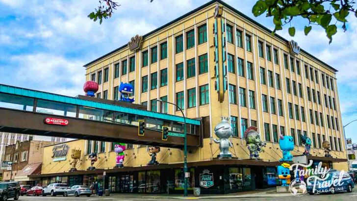 Exterior of Funko HQ, a multi story building with an elevated pedestrian bridge and multiple large Funko figures surrounding it.