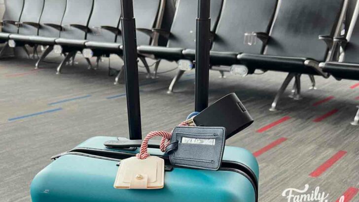 Teal suitcase in front of airport seats in gate waiting area