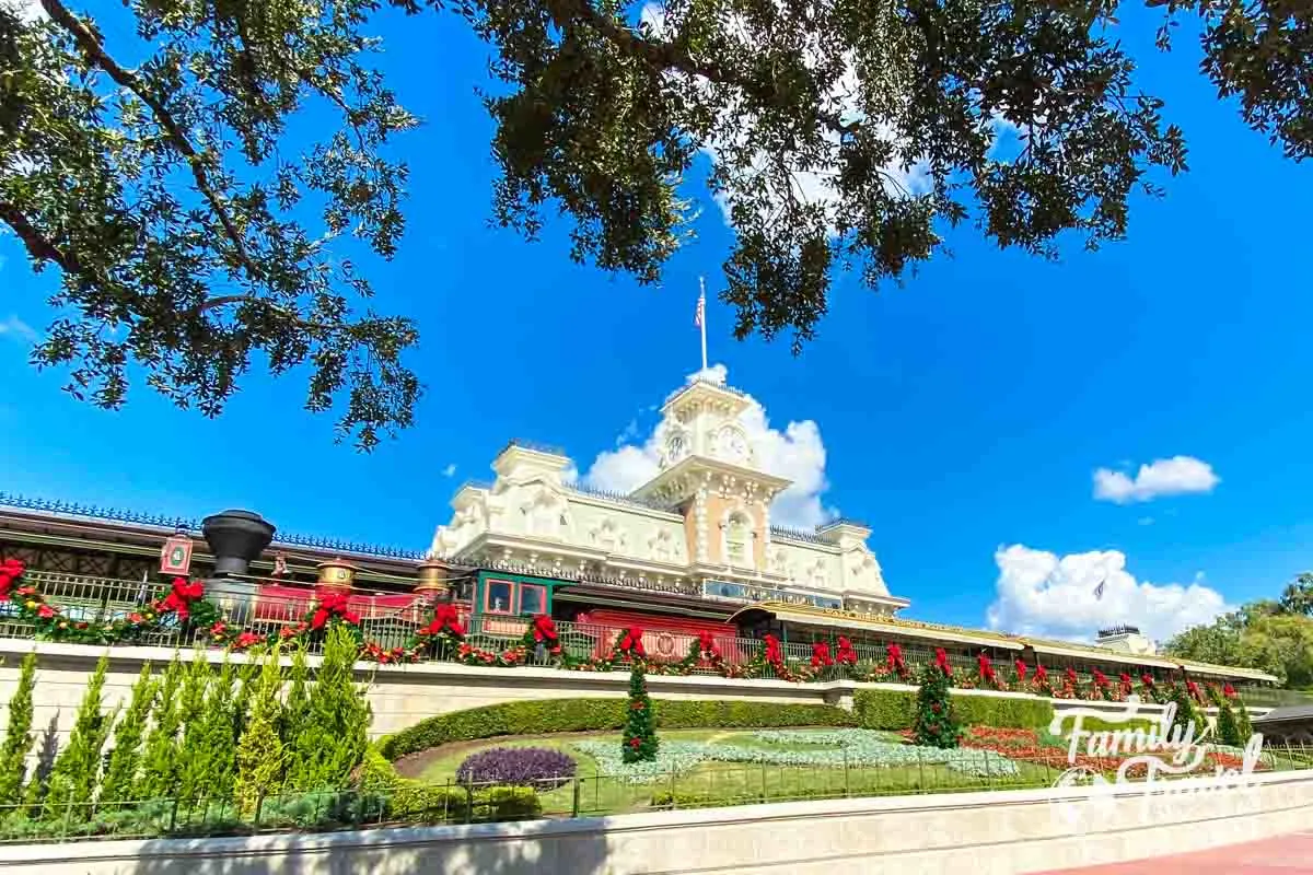 Magic Kingdom train station with train in front and Christmas decor