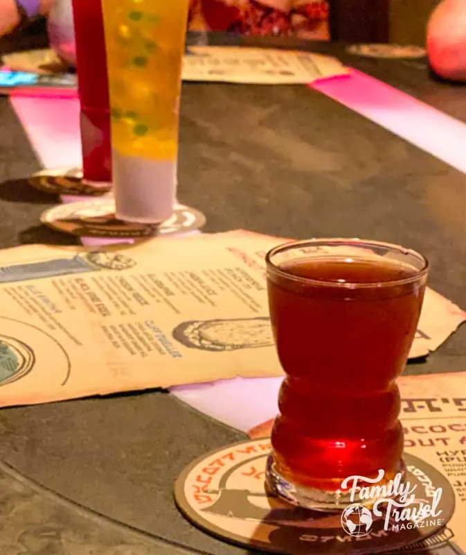 Três bebidas coloridas na mesa com menus