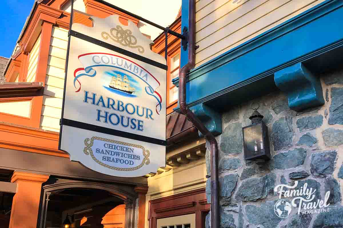 Exterior of Columbia Harbour House with cobblestone wall and sign with a boat