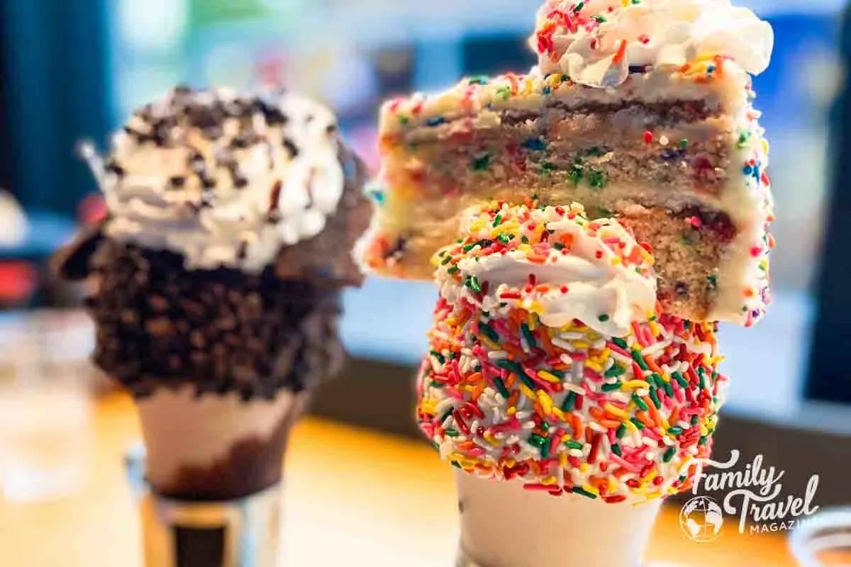 Two shakes - one with a brownie and one with a piece of cake on top