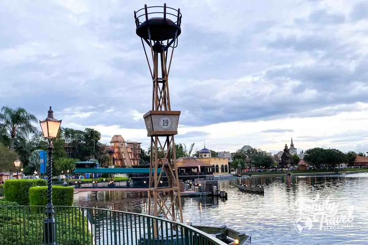 World Showcase at EPCOT from a distance with lagoon in foreground. Buildings include Mayan temple. 