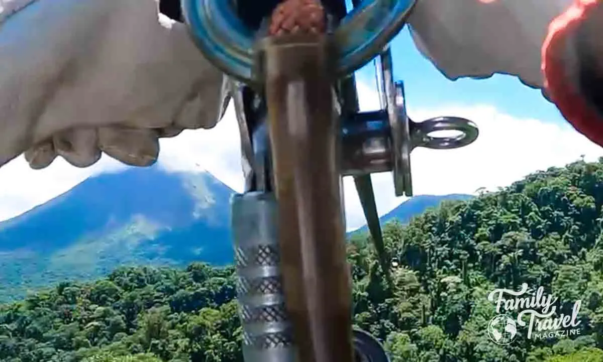 view of hands ziplining by Arenal