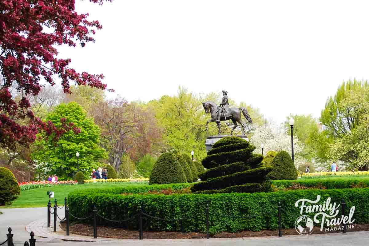 Statue of man on a horse in a park surrounded by greenery