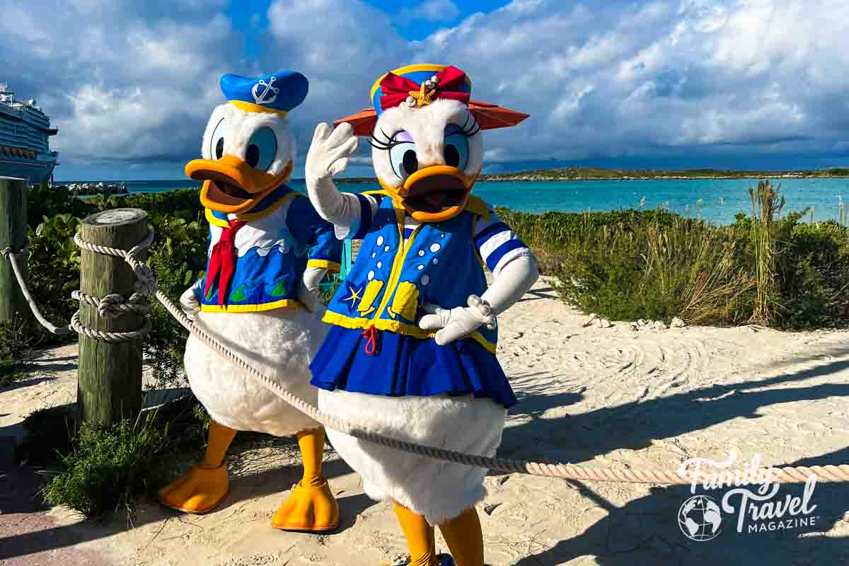 Daisy and Donald on the beach wearing their beach apparel with ship in the background