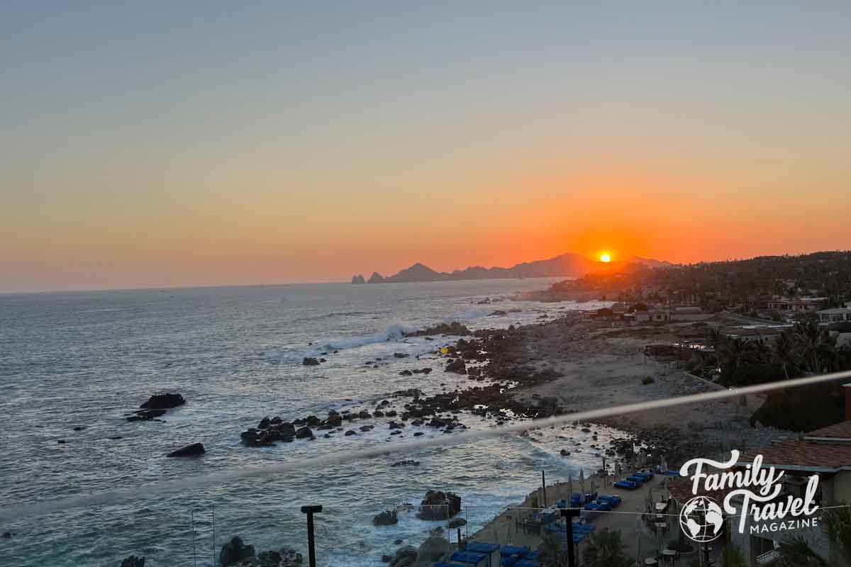 Sunset over rock cliffs with rocky waterfront area. 