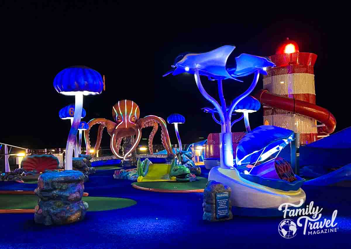 Ocean themed mini golf course with octopus, jellywish, and stingray and lighthouse in the background