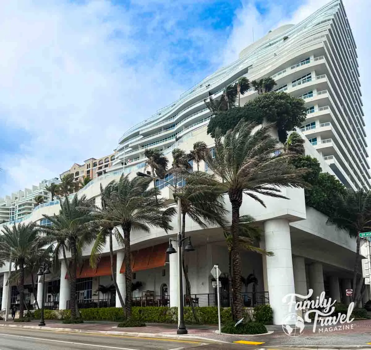 Exterior of large beachfront hotel with palm trees