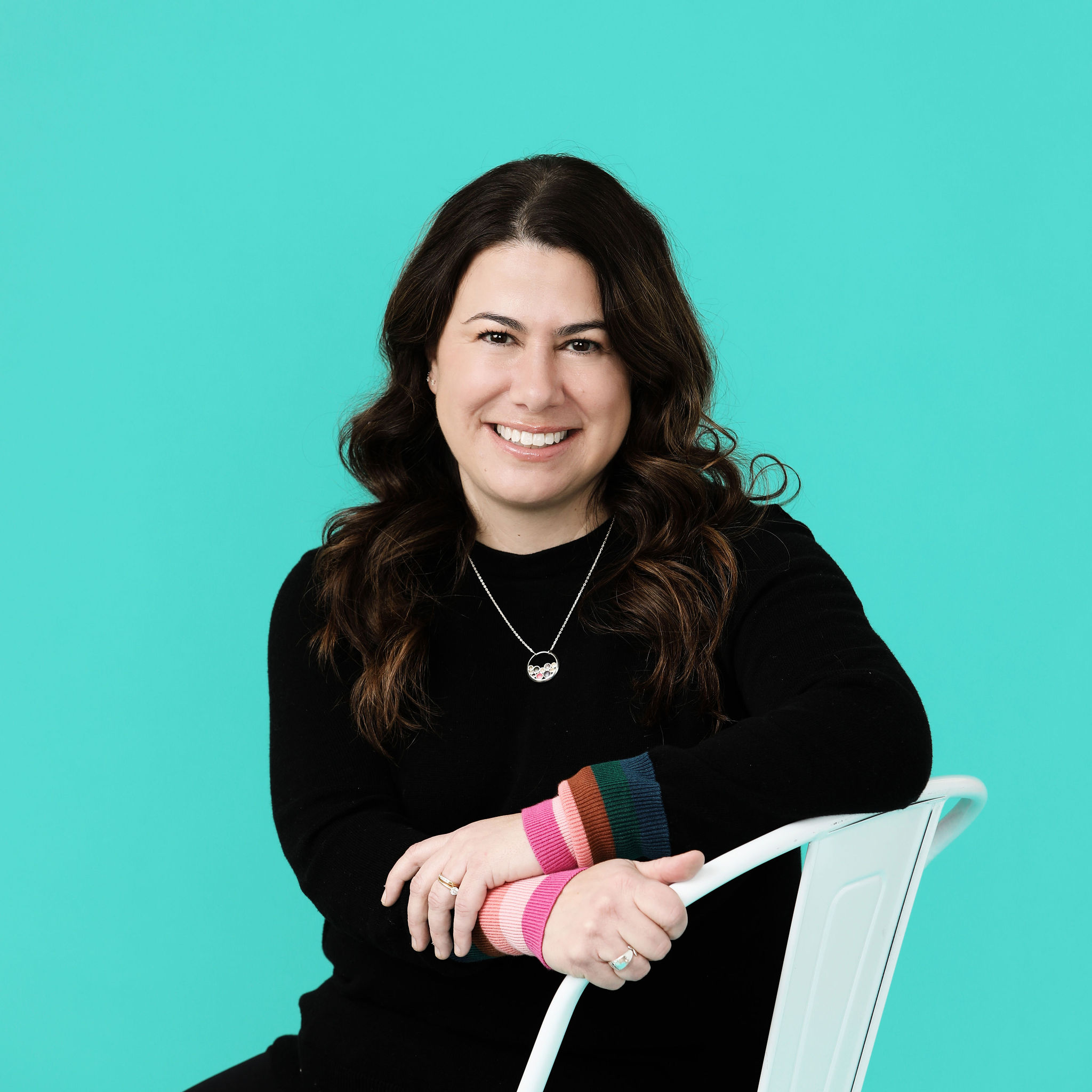 A woman sitting sideways in a chair smiling