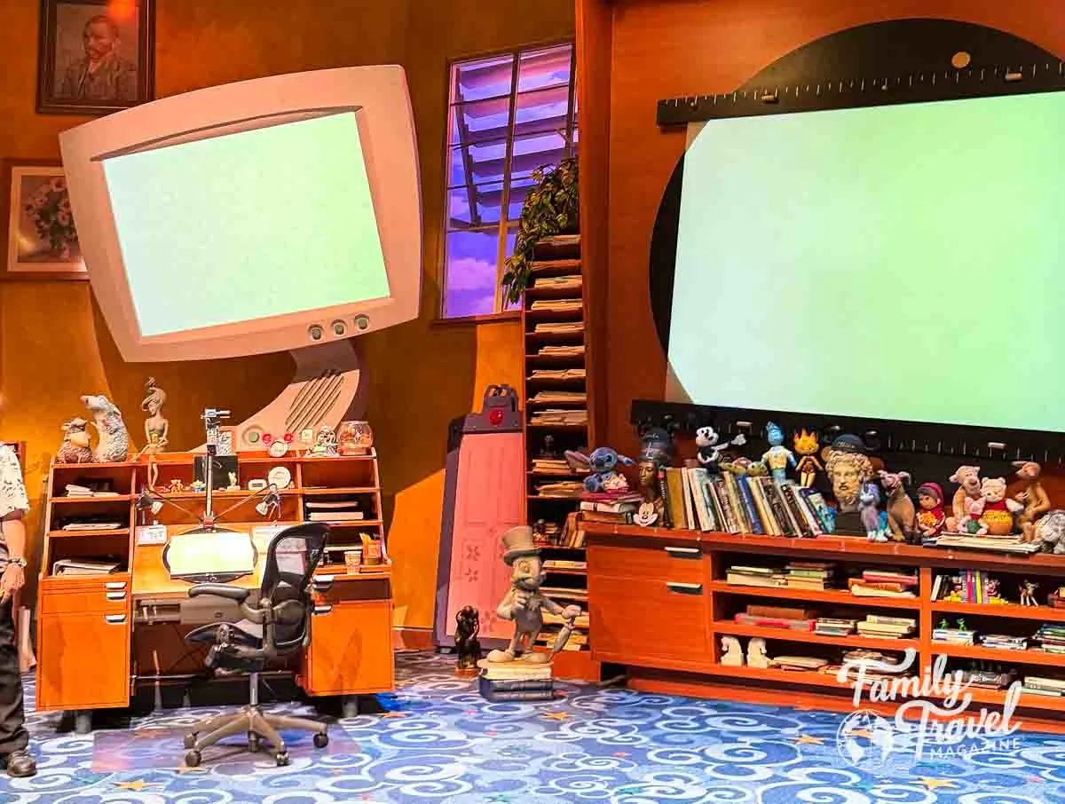 Stage for Animation Academy with books, a desk, screens, and other souvenirs. 